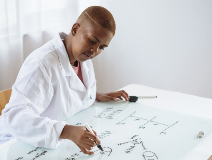 woman drawing on whiteboard wearing lab coat